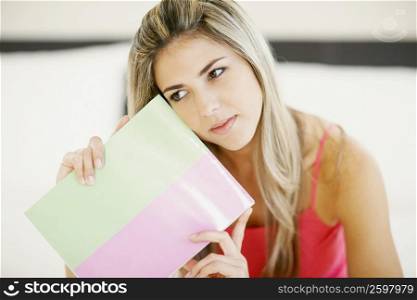 Close-up of a mid adult woman holding a file and thinking