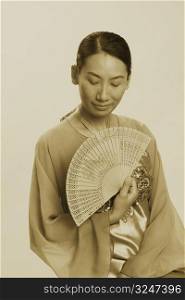 Close-up of a mid adult woman holding a folding fan with her eyes closed