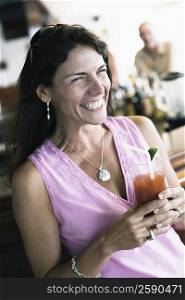 Close-up of a mid adult woman holding a glass of juice and smiling