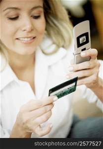Close-up of a mid adult woman holding a mobile phone and a credit card