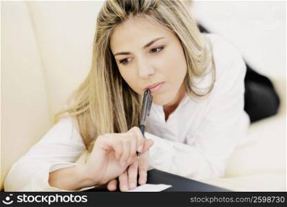 Close-up of a mid adult woman holding a pen and thinking