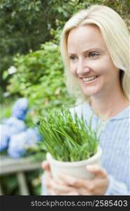 Close-up of a mid adult woman holding a potted plant and smiling