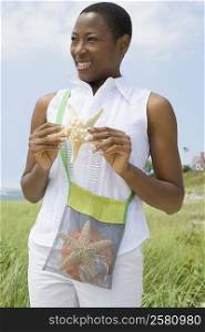 Close-up of a mid adult woman holding a starfish and smiling