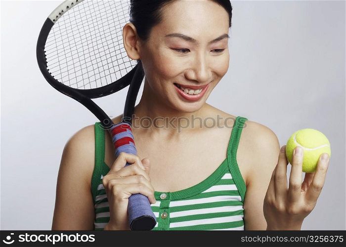 Close-up of a mid adult woman holding a tennis racket and looking at a tennis ball
