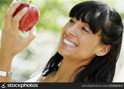 Close-up of a mid adult woman holding an apple and smiling