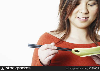 Close-up of a mid adult woman holding chopsticks and a plate