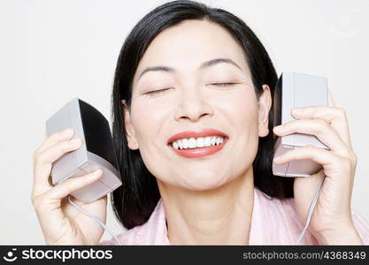 Close-up of a mid adult woman holding speakers upto her ear