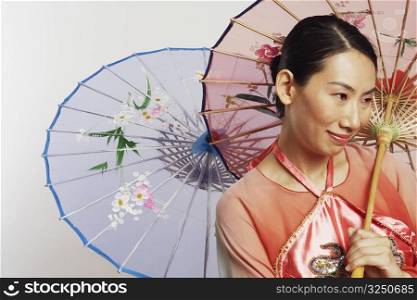 Close-up of a mid adult woman holding two umbrellas and smiling