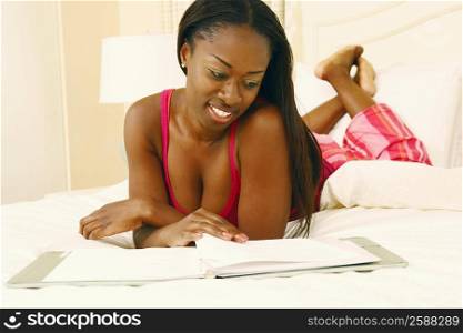 Close-up of a mid adult woman lying in bed and reading a file
