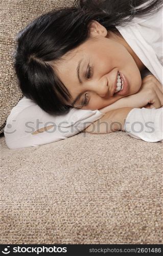 Close-up of a mid adult woman lying on a couch and smiling