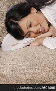 Close-up of a mid adult woman lying on a couch and smiling