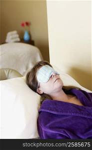 Close-up of a mid adult woman lying on massage table with a sleep mask on her eyes