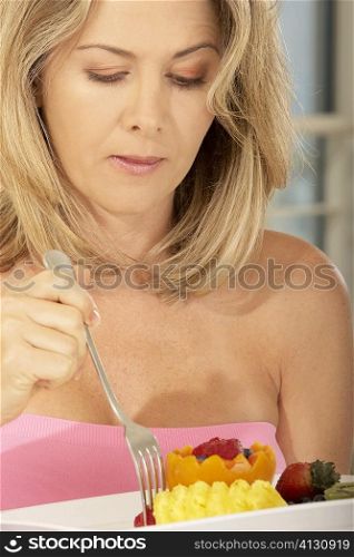 Close-up of a mid adult woman picking a strawberry from a plate