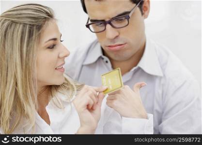 Close-up of a mid adult woman showing a credit card to a mid adult man