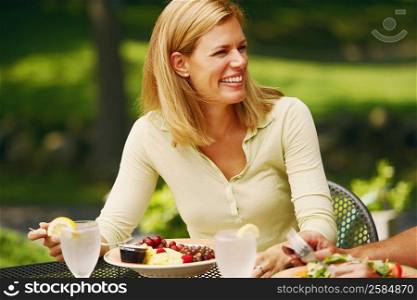 Close-up of a mid adult woman sitting at a table with a plate of salad in front of her