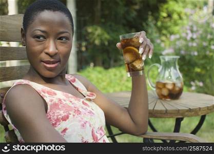 Close-up of a mid adult woman sitting on a chair and drinking ice tea