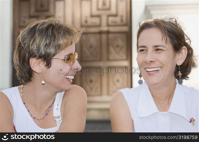 Close-up of a mid adult woman sitting with a mature woman and laughing