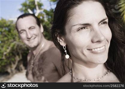 Close-up of a mid adult woman smiling with a mid adult man standing in the background