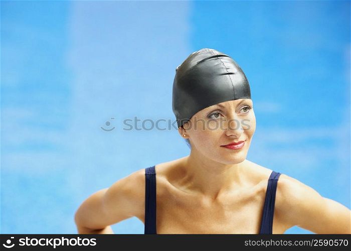 Close-up of a mid adult woman standing near a swimming pool and looking away