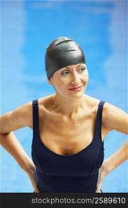 Close-up of a mid adult woman standing with arms akimbo near a swimming pool