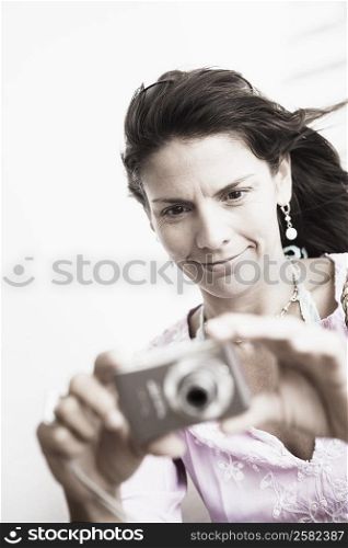 Close-up of a mid adult woman taking a picture with a digital camera