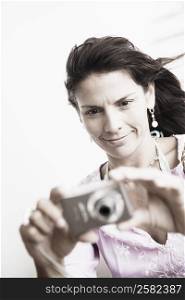Close-up of a mid adult woman taking a picture with a digital camera