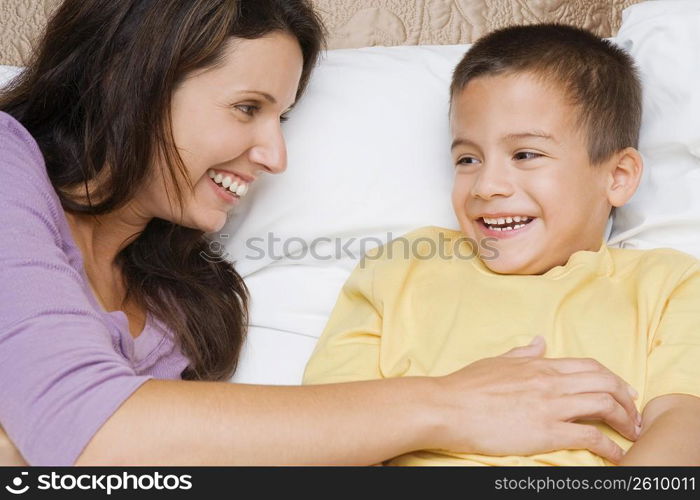 Close-up of a mid adult woman tickling her son on the bed