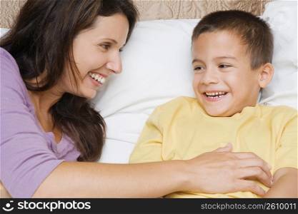Close-up of a mid adult woman tickling her son on the bed