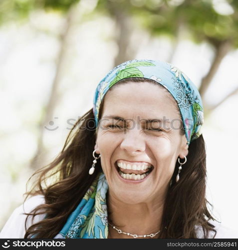 Close-up of a mid adult woman wearing a headscarf and laughing