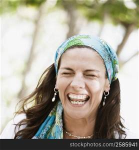 Close-up of a mid adult woman wearing a headscarf and laughing
