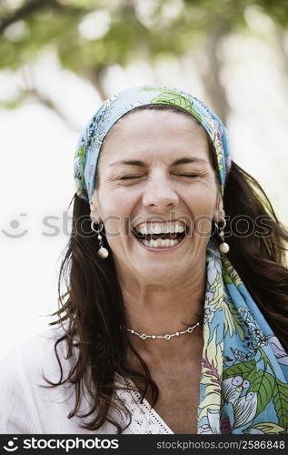 Close-up of a mid adult woman wearing a headscarf and laughing