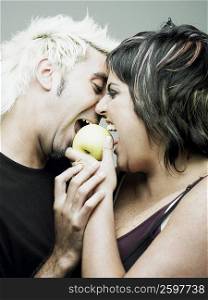 Close-up of a mid adult woman with a young man biting an apple