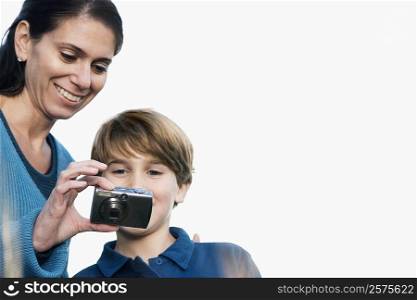 Close-up of a mid adult woman with her son looking at a digital camera