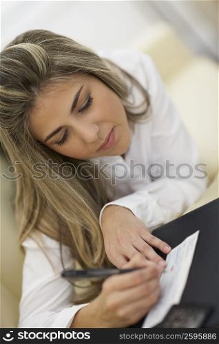 Close-up of a mid adult woman writing on a check