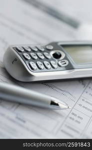 Close-up of a mobile phone and a pen on a sheet of paper