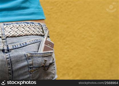 Close-up of a mobile phone in a teenage girl&acute;s back pocket