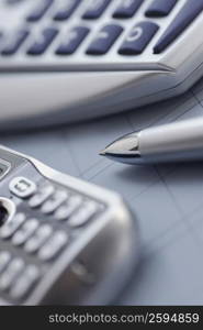 Close-up of a mobile phone with a ballpoint pen and a calculator