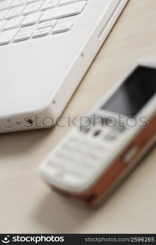 Close-up of a mobile phone with a laptop