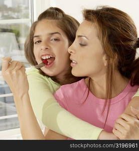 Close-up of a mother feeding her daughter strawberries