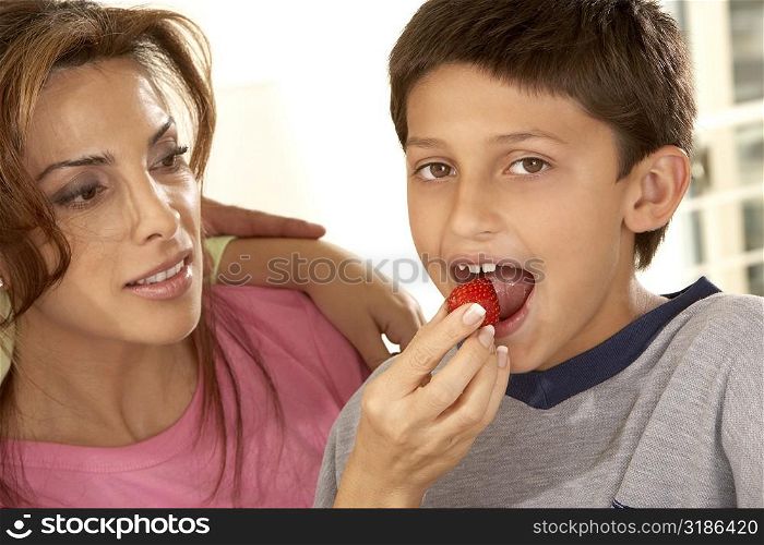 Close-up of a mother feeding her son a strawberry