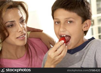Close-up of a mother feeding her son a strawberry