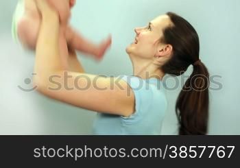 Close-up of a mother playing with her baby boy against a light blue wall