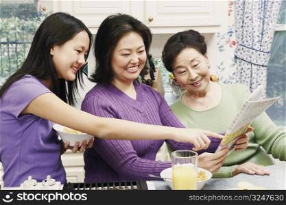 Close-up of a mother with her daughter and a senior woman reading a newspaper
