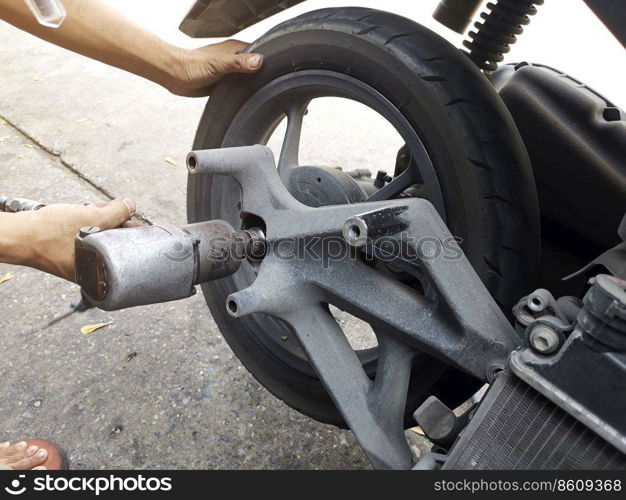 Close up of a motorcycle mechanic using an air gun to loosen the wheel nuts in a mechanical workshop