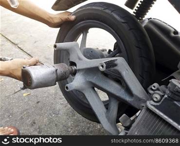 Close up of a motorcycle mechanic using an air gun to loosen the wheel nuts in a mechanical workshop