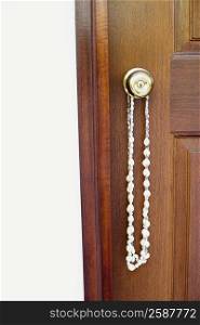 Close-up of a necklace hanging on a doorknob