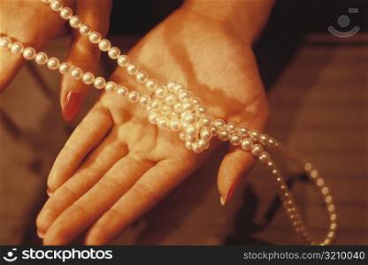 Close-up of a necklace of Mikimoto pearls in a woman&acute;s hand