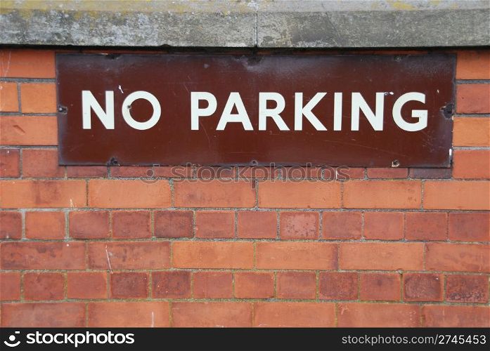 close-up of a no parking sign on a red brick wall