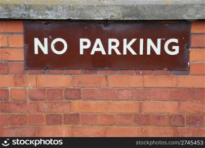 close-up of a no parking sign on a red brick wall