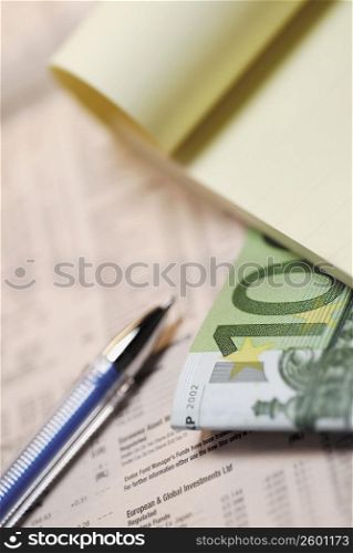 Close-up of a notepad and a pen on a financial paper